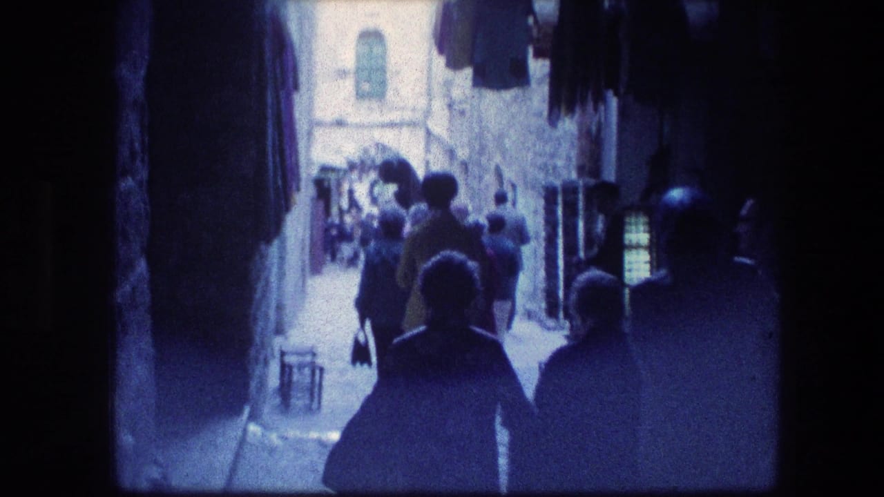 People walking through a narrow stone alley with deep shadows and bright light ahead.
