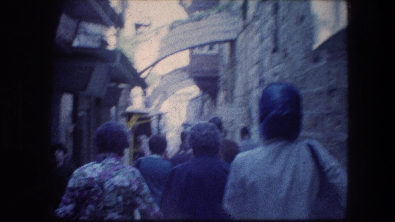 Tourist-shot 1976 Jerusalem alley view with pedestrians moving away under arched stonework and awnings.
