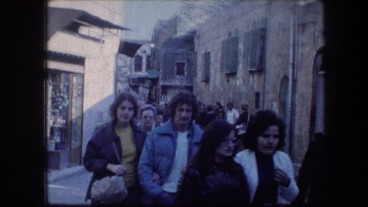 Adults in 1970s clothing walk toward the camera on a crowded Jerusalem street near the Garden Tomb.