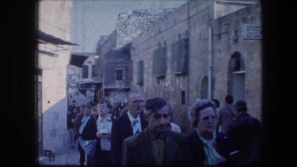 Crowded 1976 Jerusalem street scene near the Garden Tomb, with older adults and visitors walking between stone buildings.