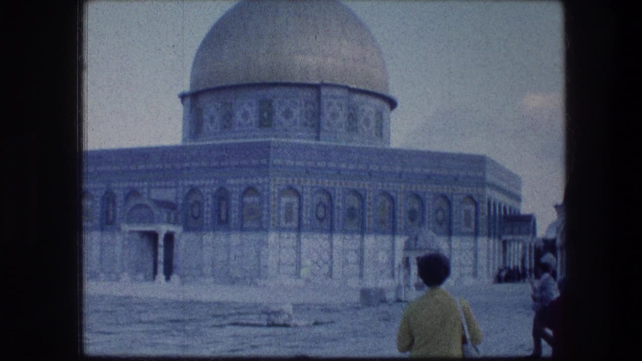 A traveler in a yellow sweater stands in the Jerusalem courtyard facing the Dome of the Rock in 1976 footage.