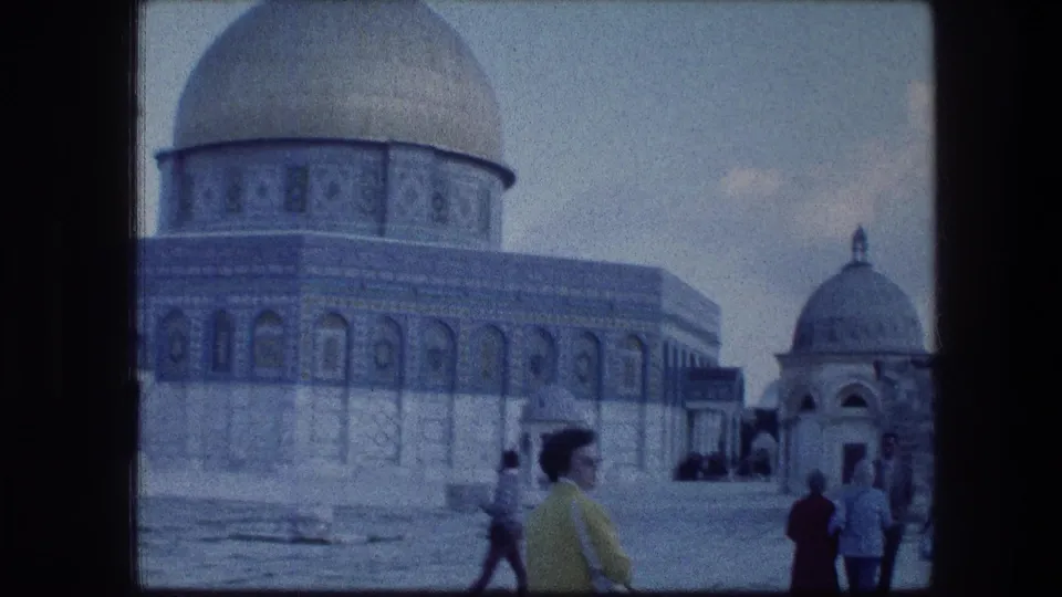 Dome of the Rock courtyard in Jerusalem with several visitors and a smaller domed structure visible at right.