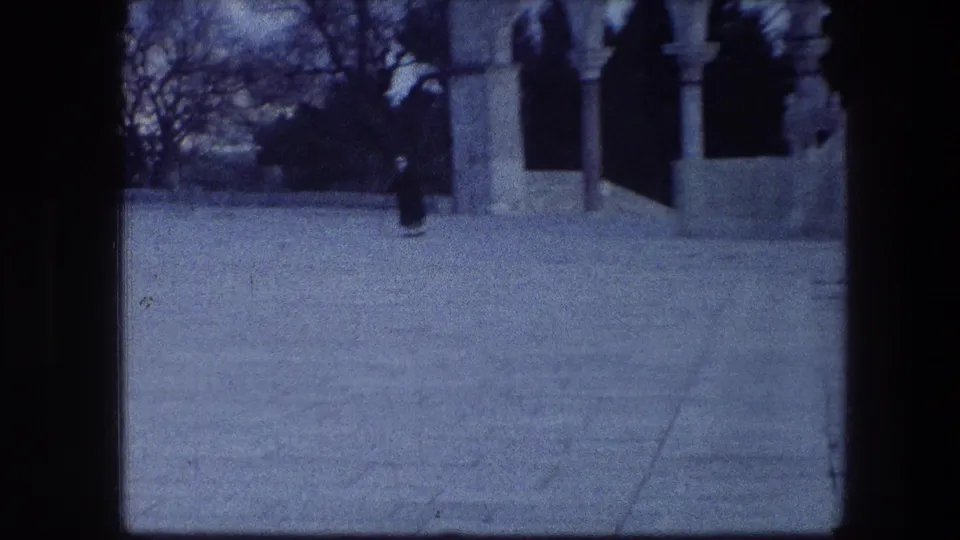 Soft 8mm frame of the Garden Tomb area in Jerusalem, with arched stonework and a lone figure crossing the courtyard.