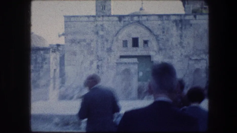Tourists in 1970s attire approach a stone entrance near domed Jerusalem religious architecture in faded 8mm footage.