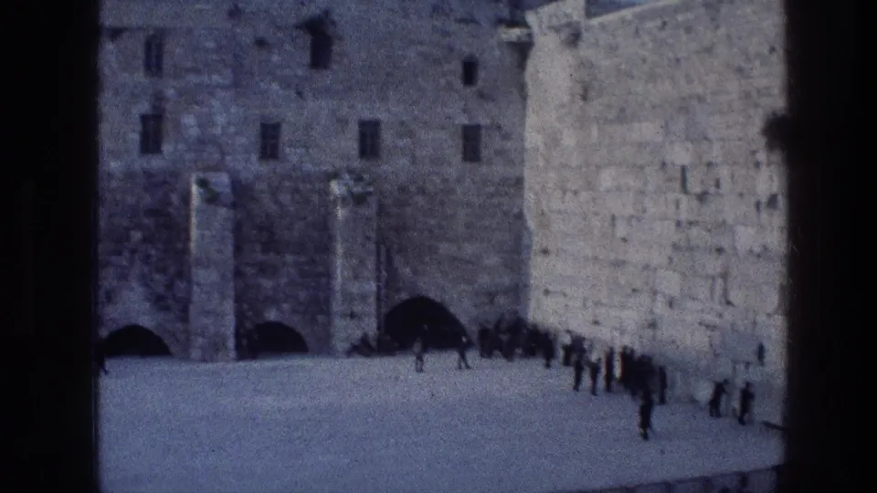 1976 8mm view of the Western Wall plaza in Jerusalem, with visitors or worshippers gathered along the large stone wall and open paved area.