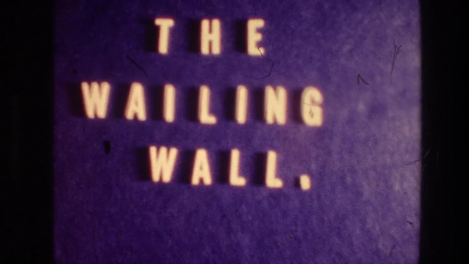 Illuminated THE WAILING WALL title card fills the frame, with 8mm grain and dark edge marks visible.