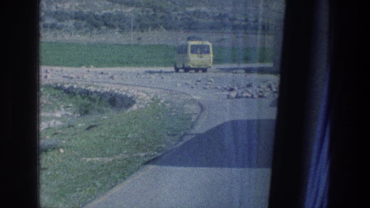 A yellow van travels on a rural road in 1970s Israel, viewed through dark vertical window or film-frame edges.