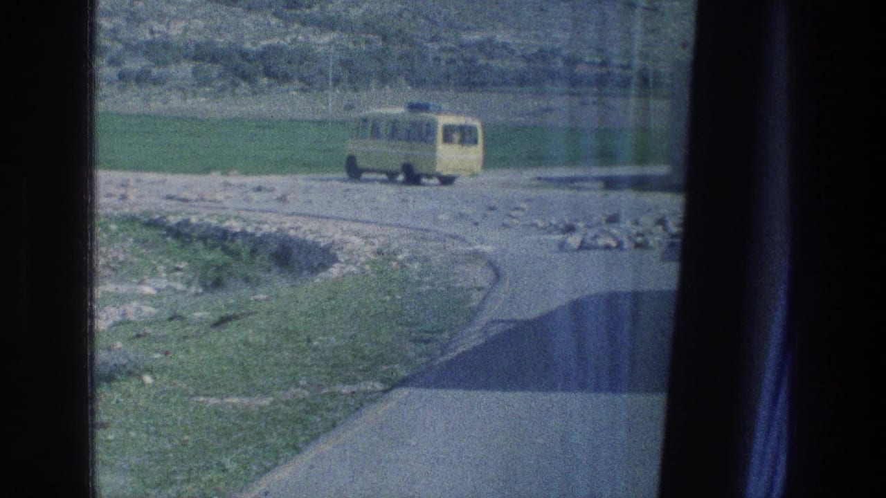 Yellow van farther along the road with fields and rocks around it.