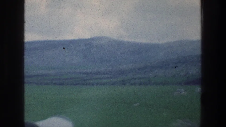 Soft 8mm view of green rural hills and distant mountains through a vehicle window, consistent with the Israel travel metadata.