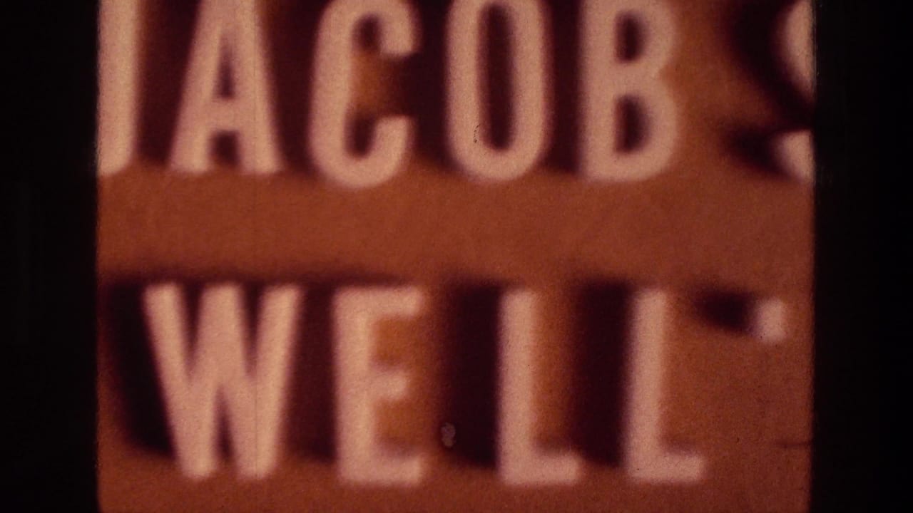 Close, cropped view of a brown sign with raised white Jacob's Well lettering.