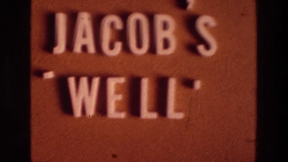 The brown Jacob's Well sign fills most of the frame, showing raised white lettering, shadowed letter edges, and warm 8mm color.