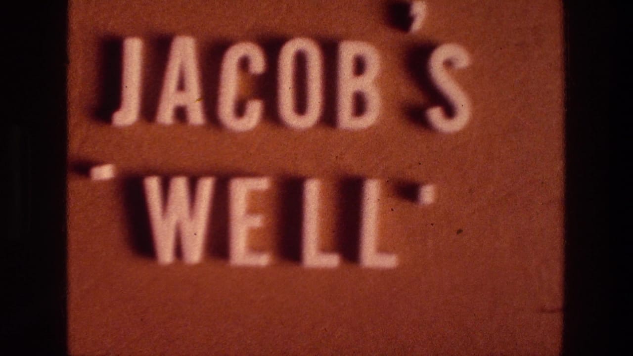 Jacob's Well sign with raised white letters against a reddish-brown background.