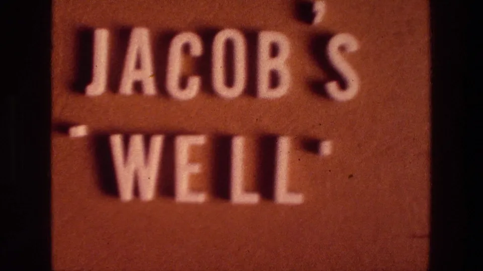 1976 8mm frame showing the Jacob's Well sign more legibly, with warm color, soft focus, and visible grain.