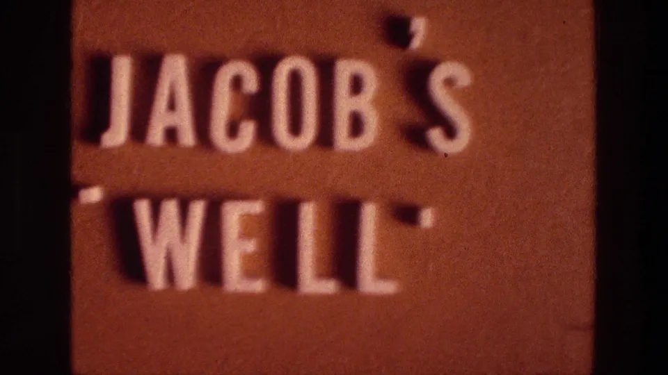 1976 8mm frame with the Jacob's Well sign filling the view, its white raised letters casting small shadows.