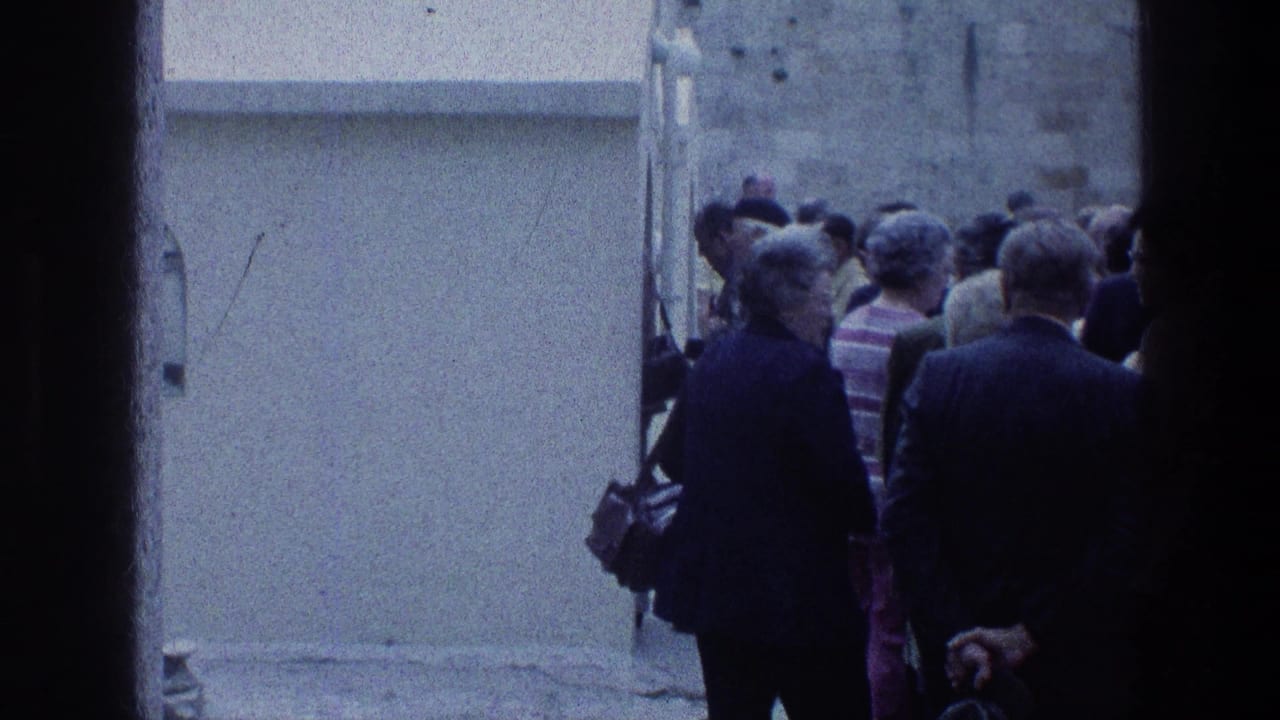 Adults stand in a narrow passage, seen from behind through a dark doorway.