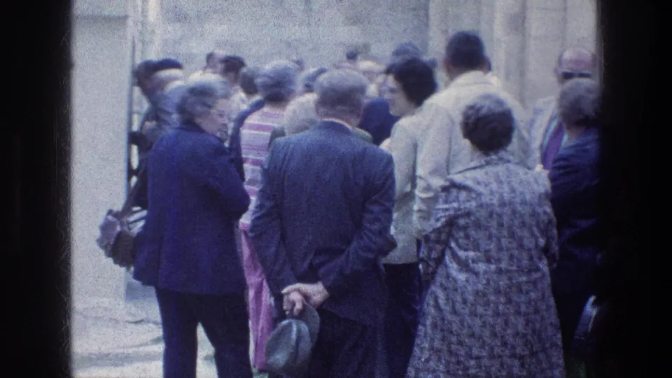 Adults at Jacob's Well in Jerusalem stand close together in a narrow passage, captured on faded 1976 8mm film.