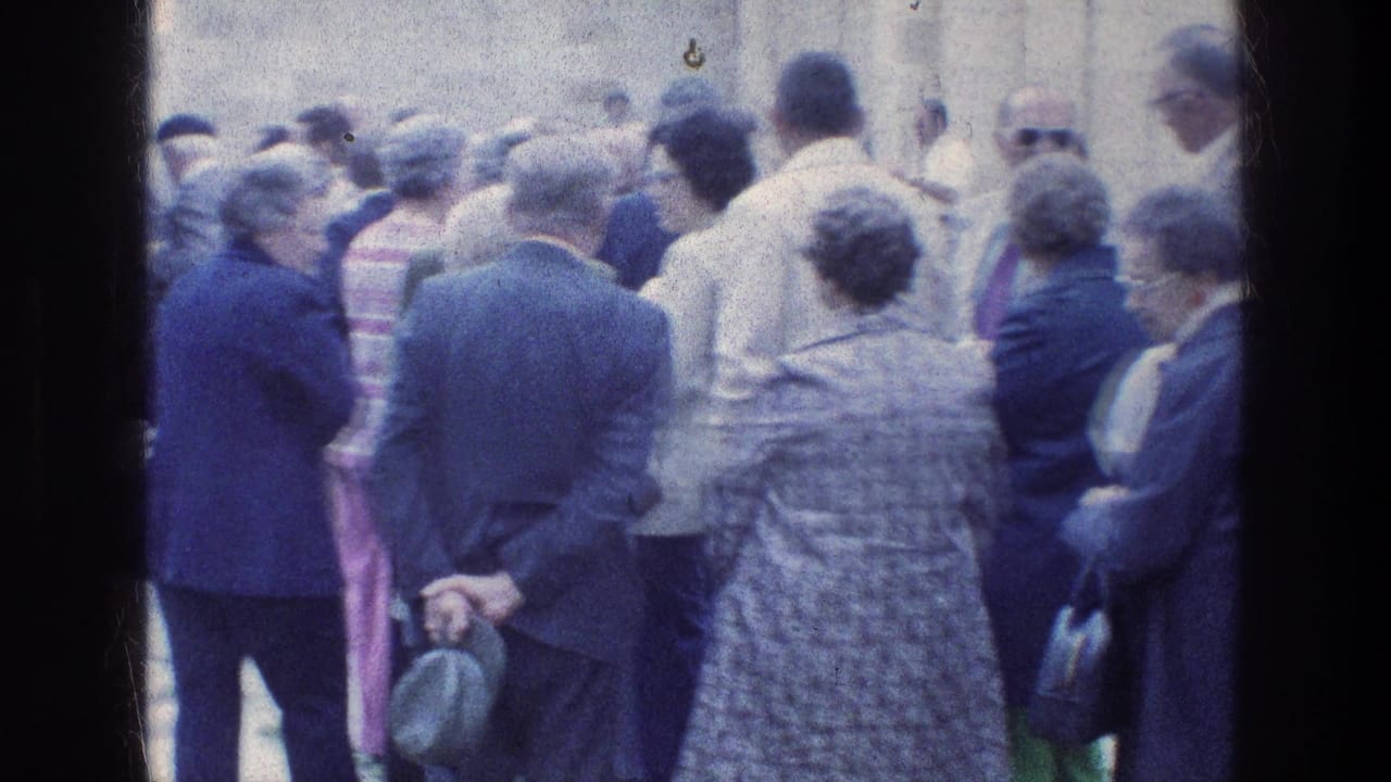 1976 8mm frame of adult visitors standing close together at Jacob's Well in Jerusalem, with stone architecture behind them.