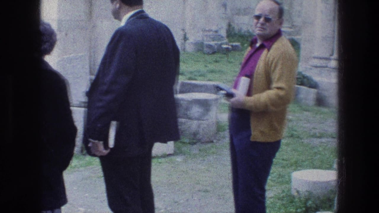 1976 8mm Jerusalem travel footage shows adult visitors near stonework at Jacobs Well, including a man in a yellow cardigan.