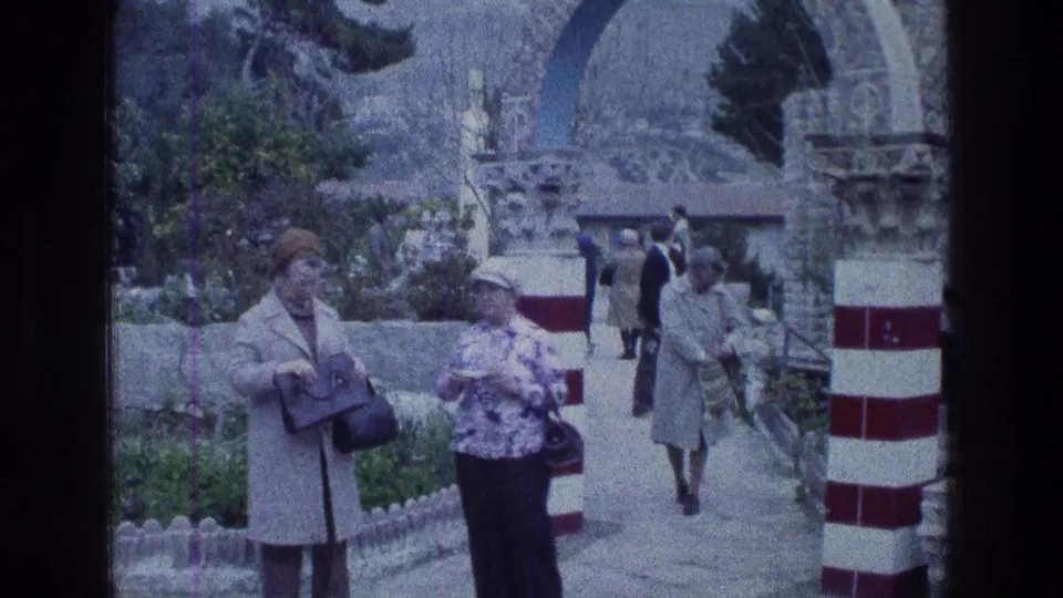 Visitors at Jacobs Well in Jerusalem stand near red-and-white columns and a stone archway in 1976 home-movie footage.