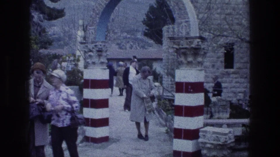 At Jacobs Well, a woman in a grey coat walks through the entrance area beside red-and-white striped columns.