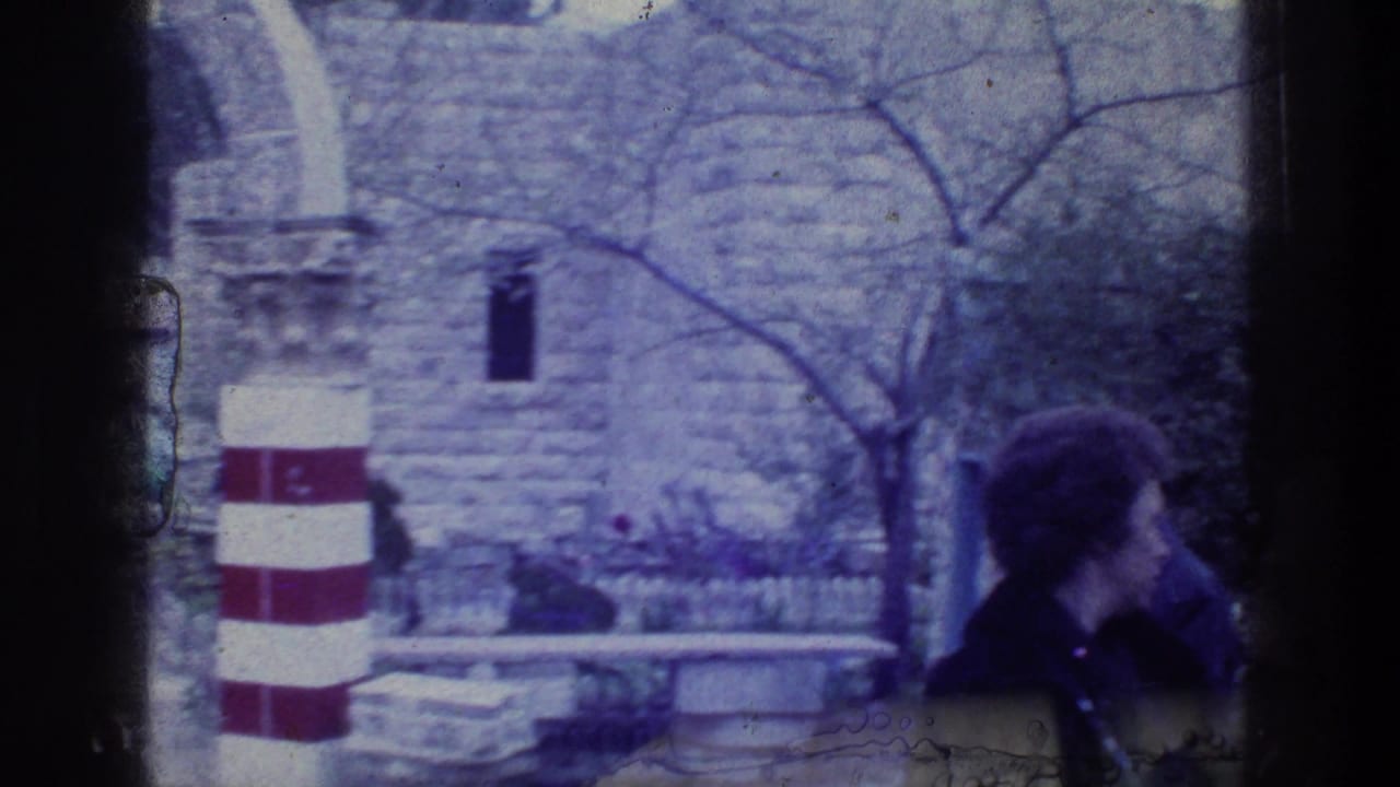 A visitor stands near striped pillars and stone arches in the courtyard.
