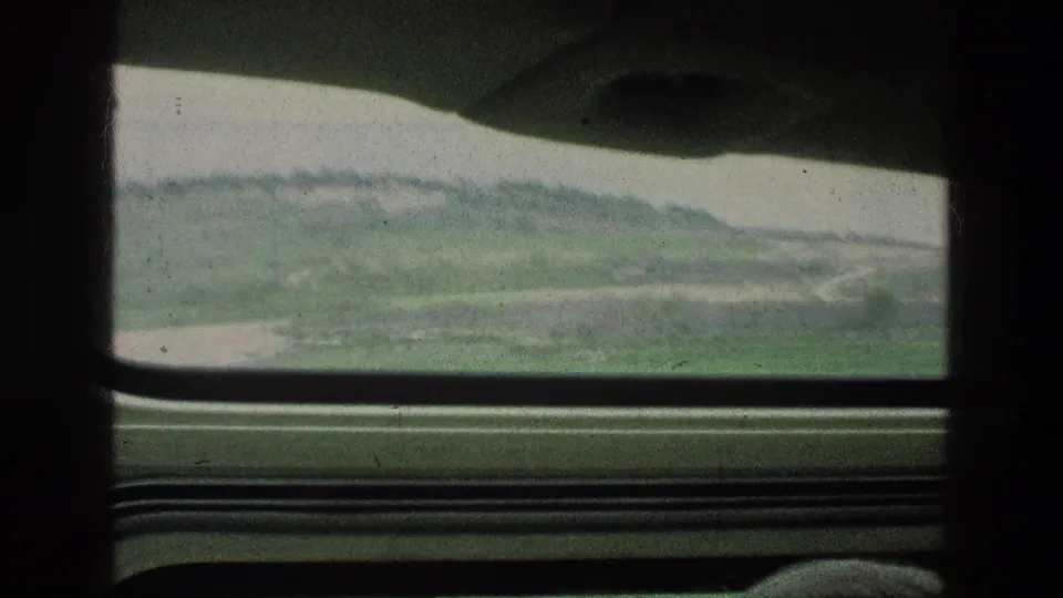1976 8mm frame showing a soft, moving car-window view of hills and roadside terrain near Jacobs Well in Jerusalem, Israel.