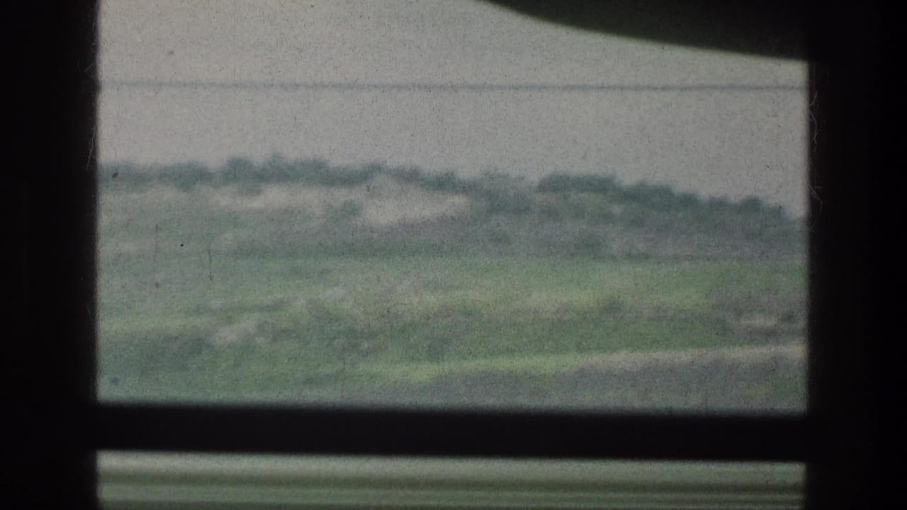 Distant green hillside viewed through the upper right section of a window.