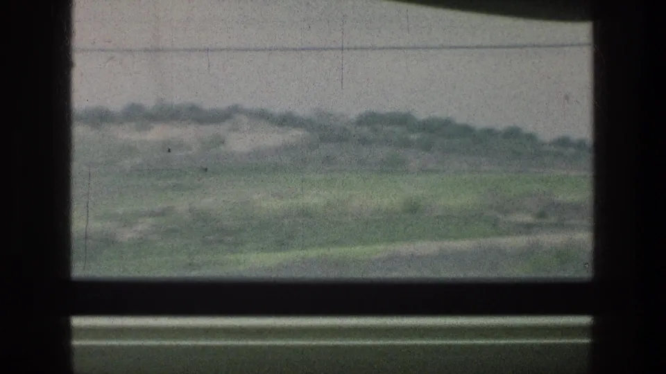 1976 8mm view through a vehicle window toward green fields, distant trees, and an overcast sky near the listed Jerusalem area.