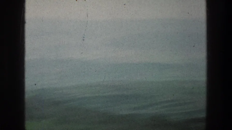 Soft 8mm view of distant rolling plains and pale sky in the Jacobs Well Jerusalem clip, with dark foreground framing visible.