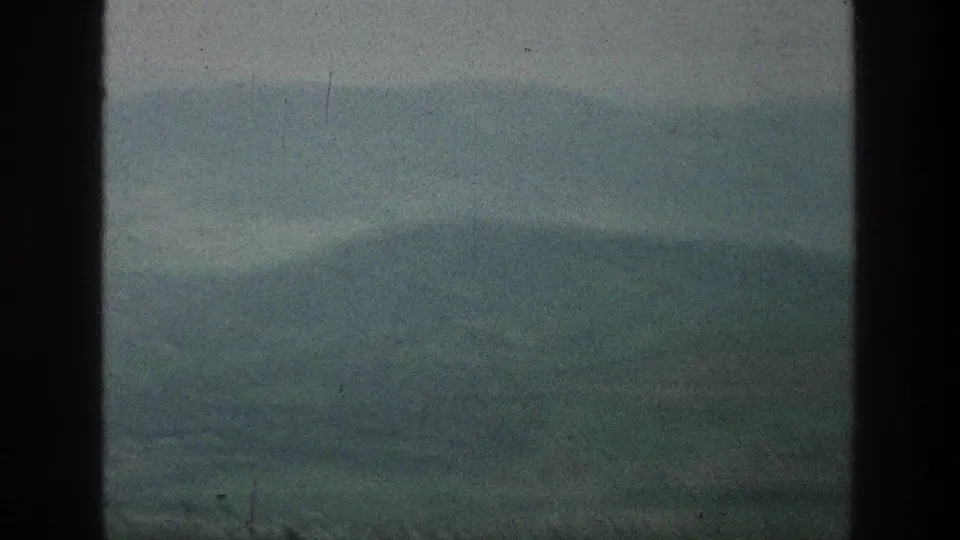 Muted 8mm frame of distant hills and open land near the listed Jacobs Well Jerusalem location, with visible grain and soft focus.