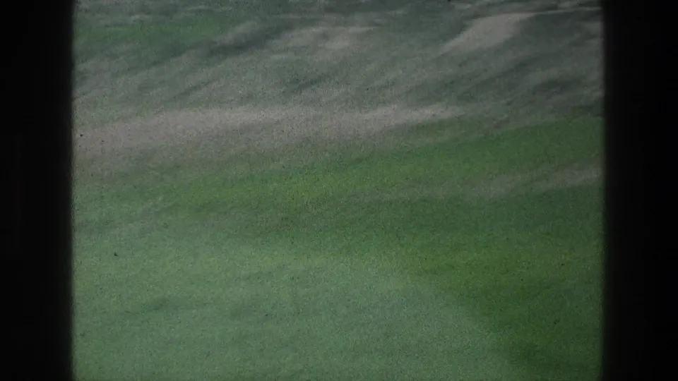 Soft 8mm landscape near Jacobs Well metadata, showing a green hillside, pale path, and dark vertical edges from the filming position.