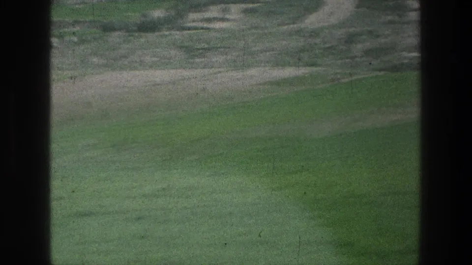 1976 8mm field view associated with Jacobs Well metadata, with muted greens, pale paths, and dark framing at the edge.