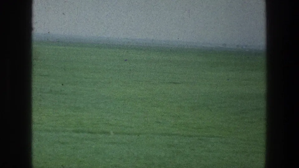 1976 8mm home-movie frame of a low green landscape near the supplied Jacobs Well Jerusalem Israel location, with hazy sky and dark foreground edges.