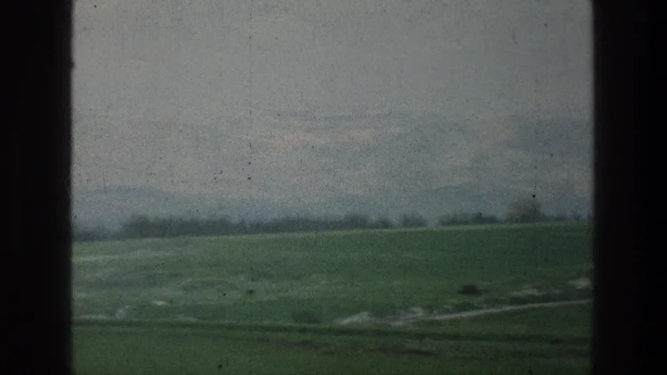 1976 8mm countryside view near Jacobs Well, Jerusalem, with green fields, a light path, and soft distant hills.