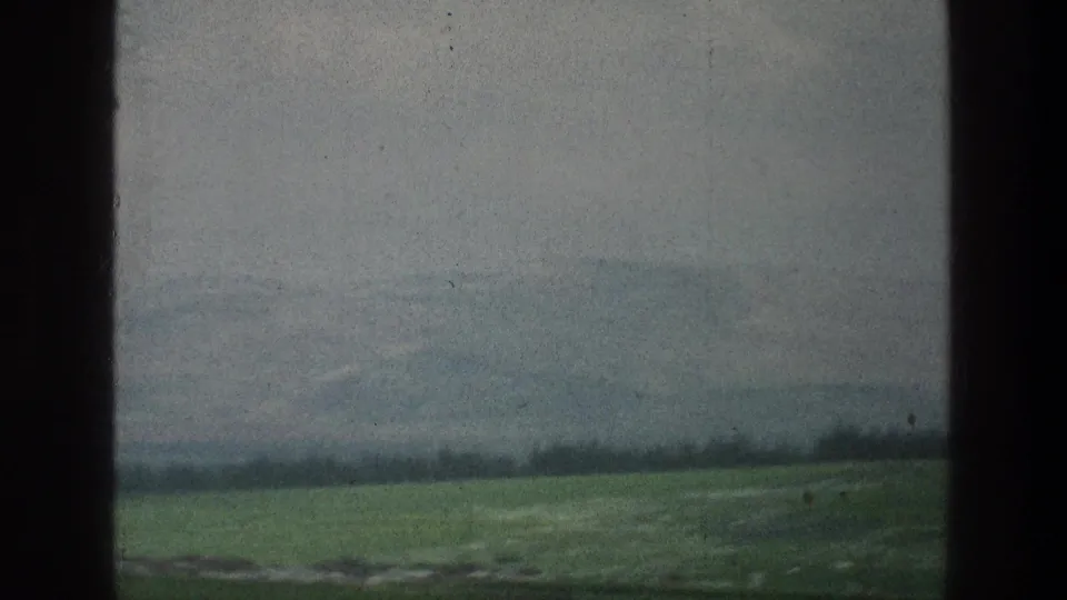 Faded 1976 8mm frame near Jacobs Well, Jerusalem, showing hazy green countryside through dark window-like borders.