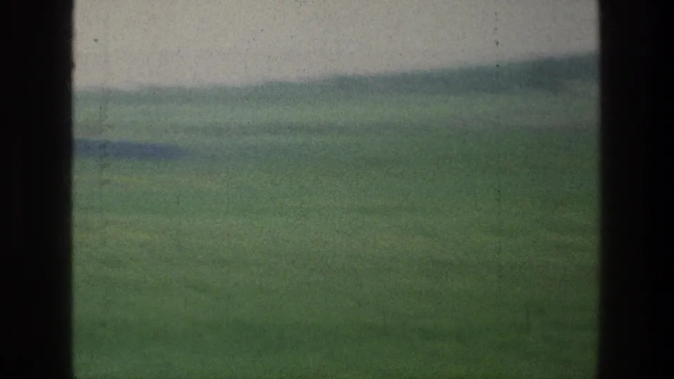 1976 8mm rural landscape near Jacobs Well, Jerusalem, with blurred green fields and a low distant horizon from a moving view.