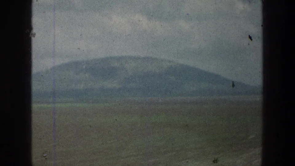 1976 8mm travel frame showing a distant hill across open fields in the Jacobs Well Jerusalem, Israel metadata location.
