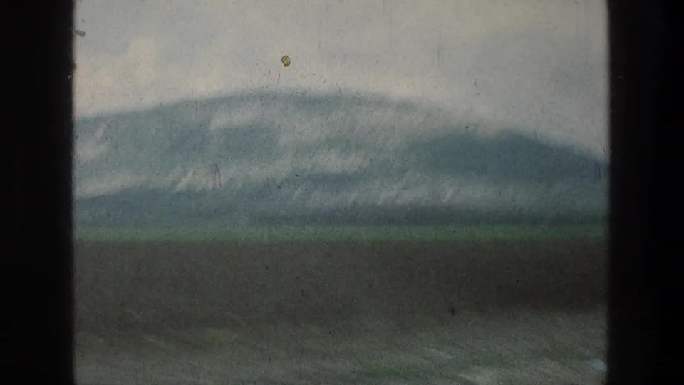 Vintage 8mm view of grey mountains and green-brown fields in the Jacobs Well Jerusalem, Israel metadata location.