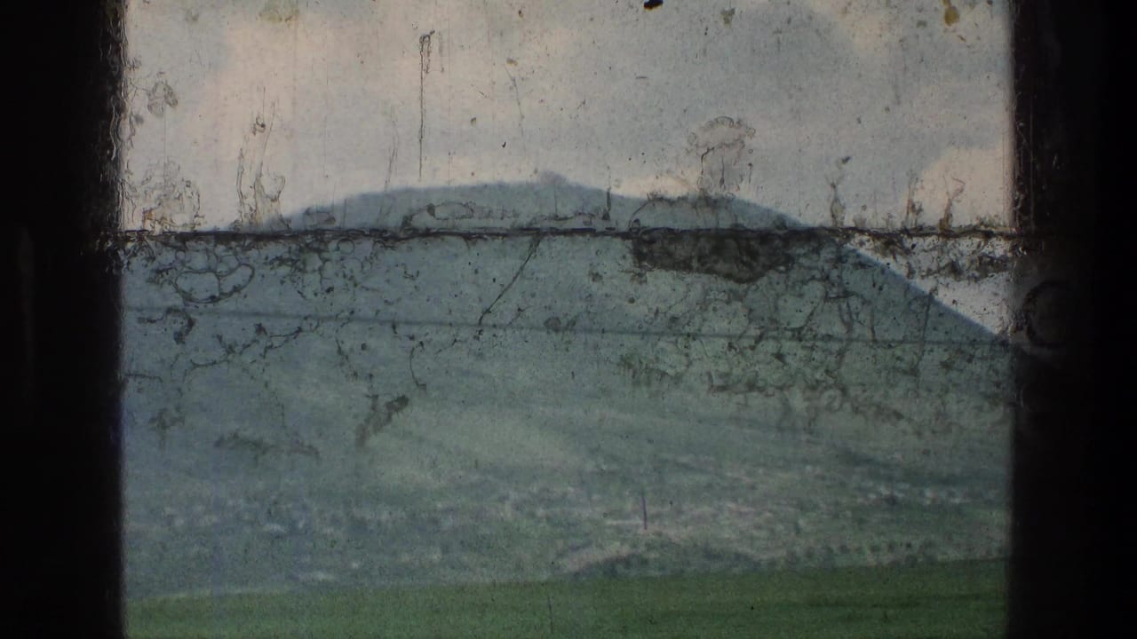 1976 8mm home-movie frame of a green hillside near the stated Jerusalem-area location, crossed by a power line and marked by film scratches.