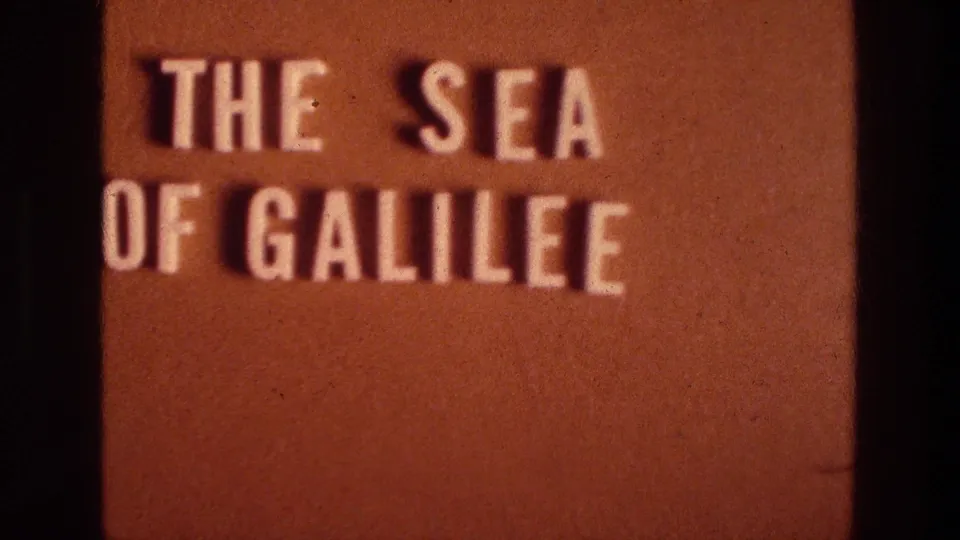 The Sea of Galilee title card remains on screen, with white lettering, brown background, gate edges, and visible 8mm film wear.