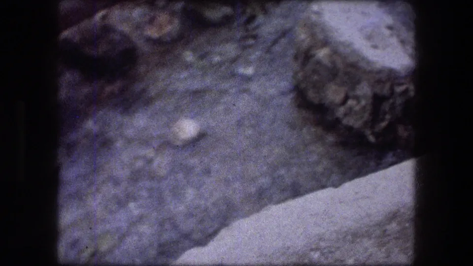 1976 Jericho 8mm close-up of a rocky spring or stream area with water, stones, and a pale edge crossing the lower frame.