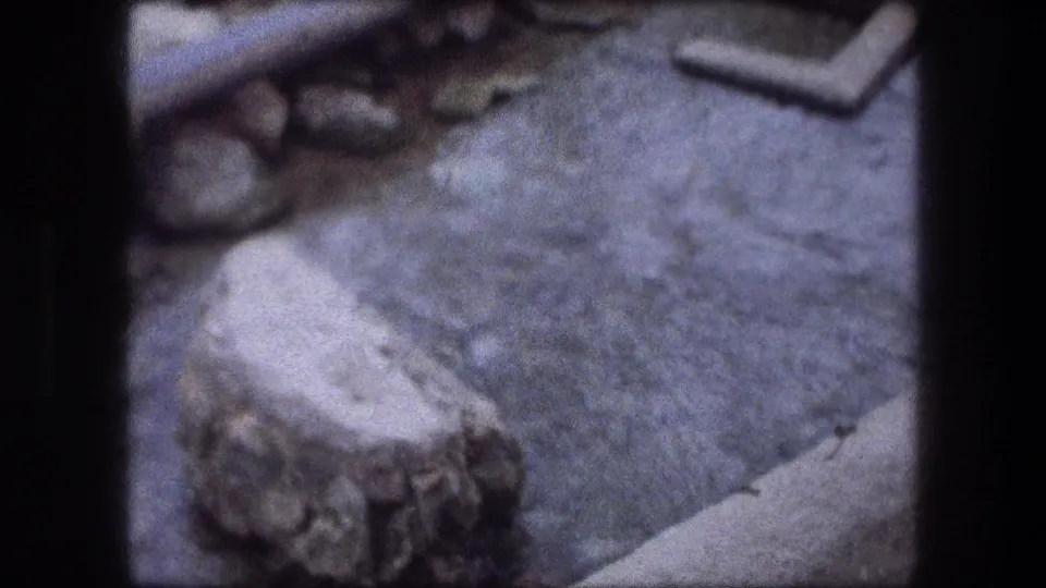 1976 Jericho 8mm frame showing shallow water, stones, and a pale edge across a rocky stream bed near the end of the clip.