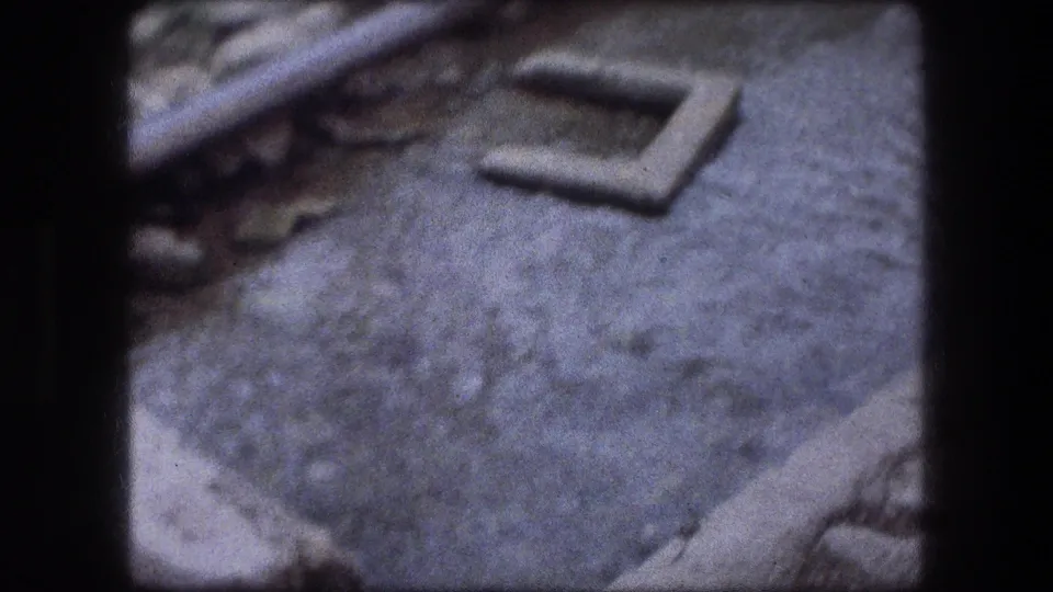 1976 Jericho 8mm view of a shallow murky stream beside rough concrete and stone banks.