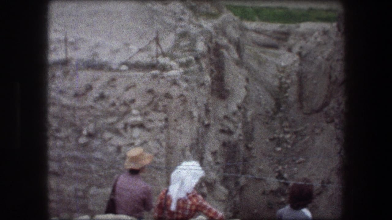 Visitors stand at the edge of a rocky excavation trench.