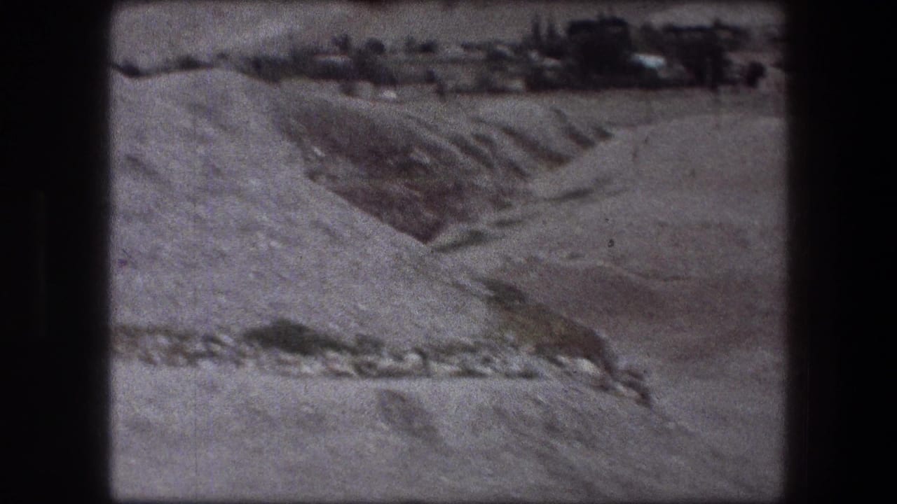 Wide view of a dry excavation slope with a darker trench and distant rough ground.