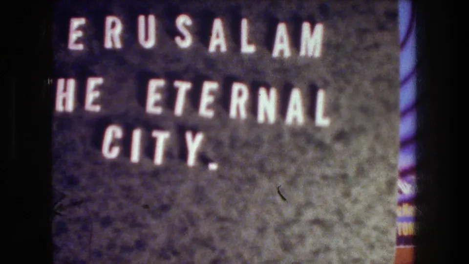 1976 Jerusalem travel-film title card with white block letters on a dark textured background and visible 8mm grain.