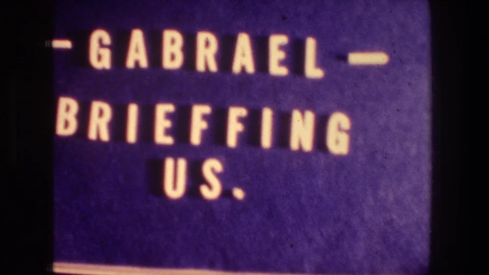 Close 1976 8mm title-card frame with blue background and white letters spelling "GABRAEL BRIEFFING US."