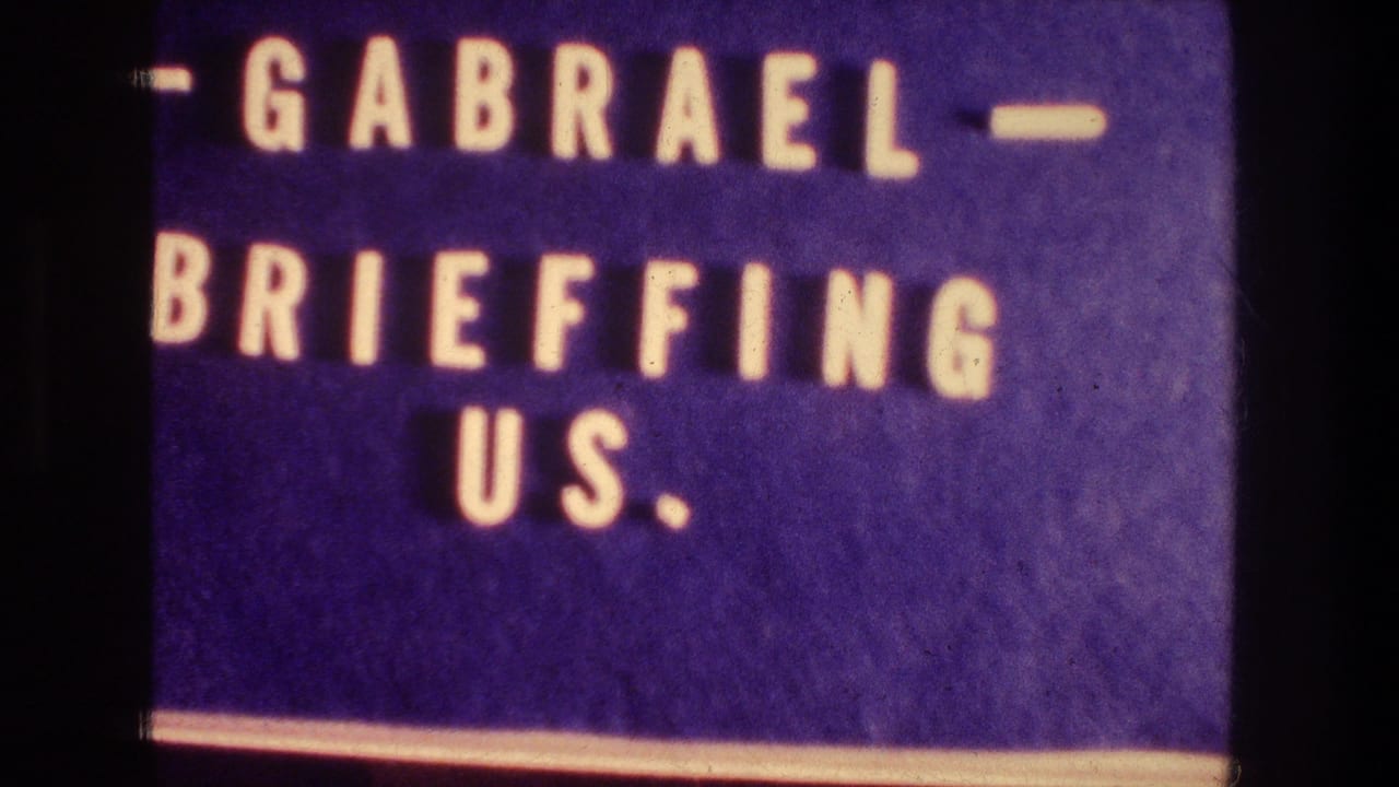 1976 home-movie title card reading GABRAEL BRIEFFING US, photographed with soft focus and purple color cast.