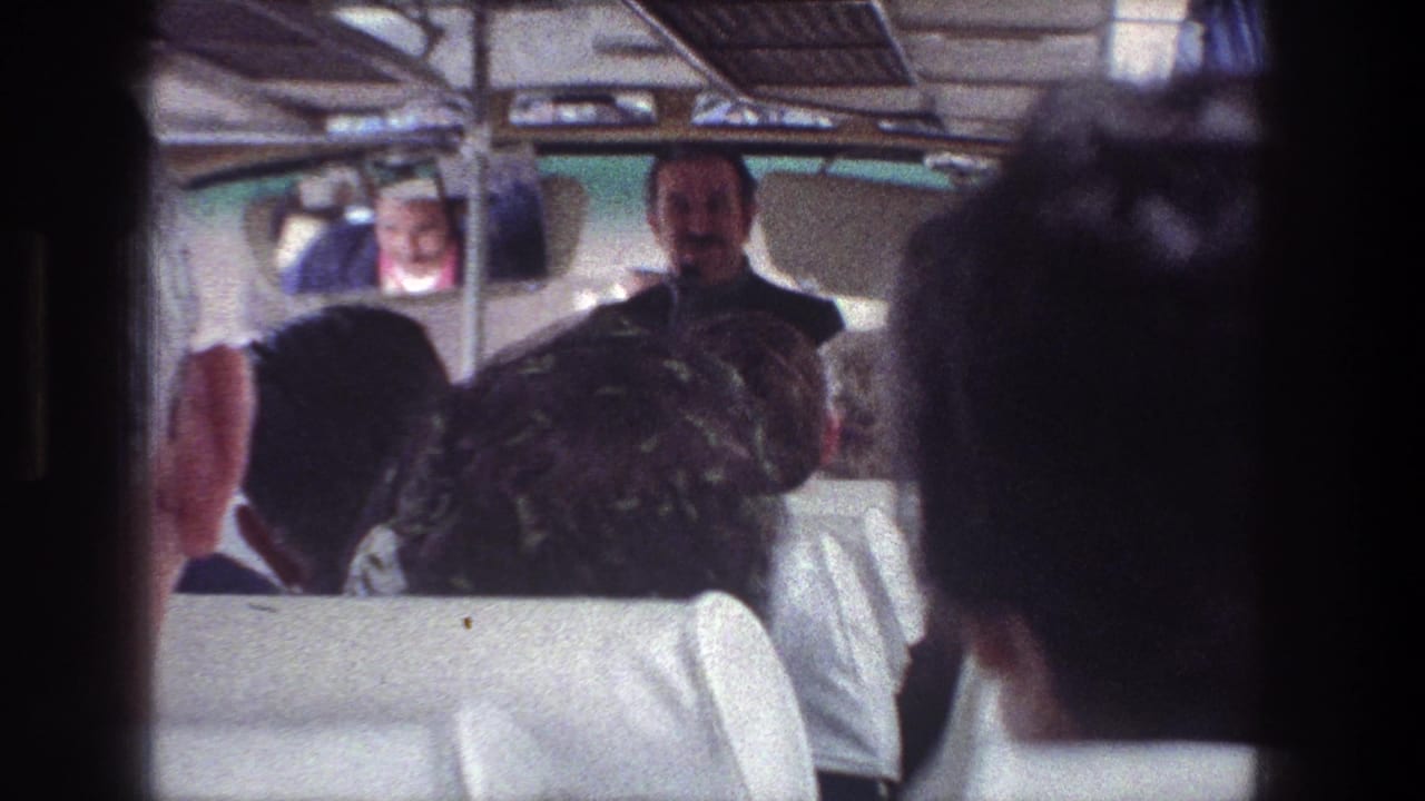 1976 Jerusalem tour-bus interior with seated passengers facing a guide at the front of the aisle.