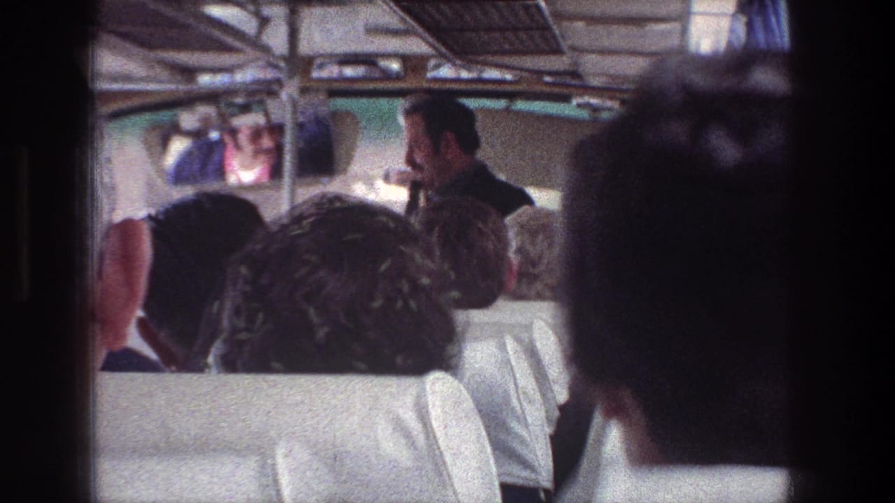 Jerusalem tour-bus passengers watch as the guide turns near the front of the bus in 1976 home-movie footage.